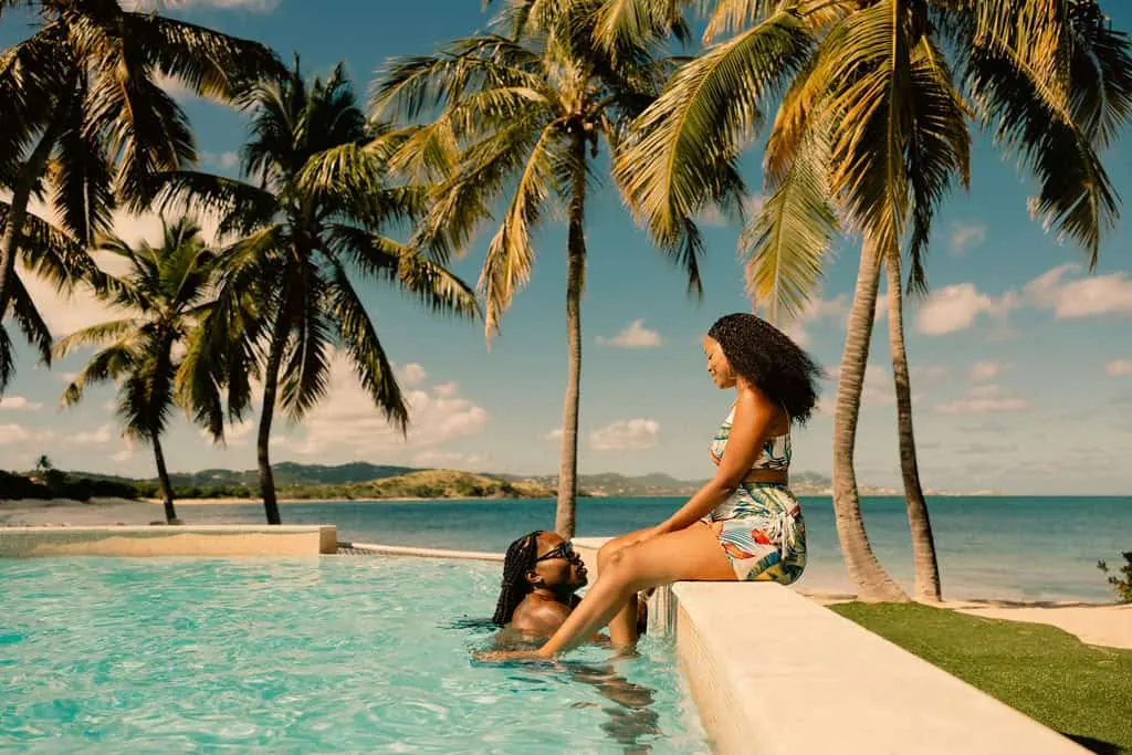 Romantic couple at an infinity pool with palm trees and turquoise Caribbean ocean in the US Virgin Islands