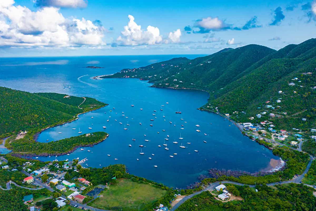 Aerial view of Coral Bay harbor on St. John's east end with sailboats anchored in deep blue waters surrounded by lush green hills