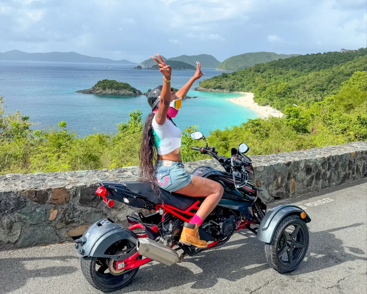 Woman on a trike at Trunk Bay overlook on St. John, USVI with turquoise Caribbean waters and lush green hills